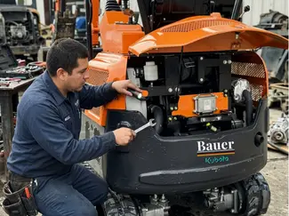 Técnico revisando mini excavadora Bauer